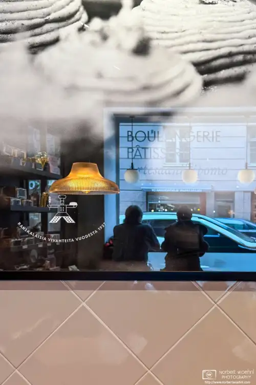 While having lunch at a café in the Kruununhaka district of Helsinki, Finland, I noticed this reflection of other customers in a framed image of pastries.