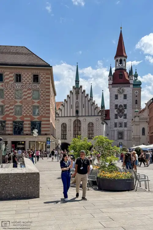 On Marienplatz in the city center of Munich, Germany, two people are having a chat during lunch break. The white building in the back is the Old Town Hall.