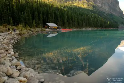 The boathouse and an adjacent peak are reflected off the crystal-clear surface of Lake Louise in Banff National Park, Alberta, Canada.