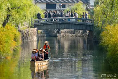 ﻿In the historic Bikan district of Kurashiki in Okayama Prefecture, Japan, a boat is gliding across a willow-lined canal.