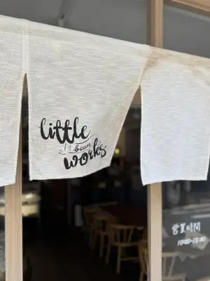 Noren (fabric divider) with shop logo hung at the entrance to Little Bean Works, a cafe in the Itabashi Ward of Tokyo, Japan.