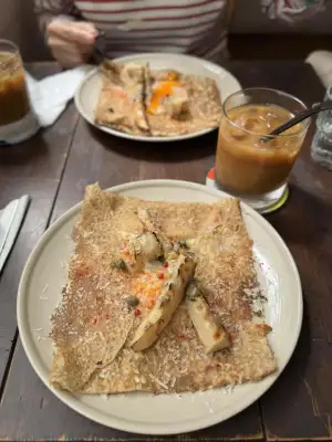 Buckwheat galette with bamboo shoots, blue cheese, egg, ham, and a glass of iced coffee.
