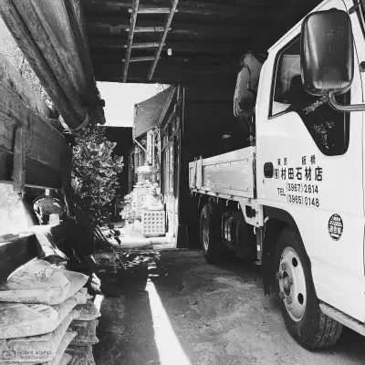 High-contrast monochrome photograph of a scene at Murata Stone Works, a small company making stone sculptures and other stone products in the Hasunuma-cho neighborhood of Itabashi Ward in Tokyo, Japan.