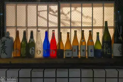 Emptied bottles of alcoholic drinks are lined up in a restaurant window in the Itabashi ward of Tokyo, Japan.