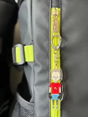 Detail of key ring with illustration of a male character in kickboxing sports gear, attached to a sports bag.