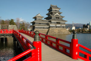 A view of Matsumoto Castle in Nagano Prefecture, Japan, across a red bridge on its western side.