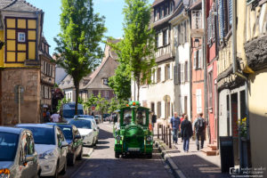 A colorful "tourist train" vehicle is seen navigating the old cobblestone streets of Colmar in Alsace, France.