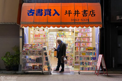 A customer is weighing a purchase at a small neighborhood bookstore in Itabashi-ku, Tokyo, Japan.