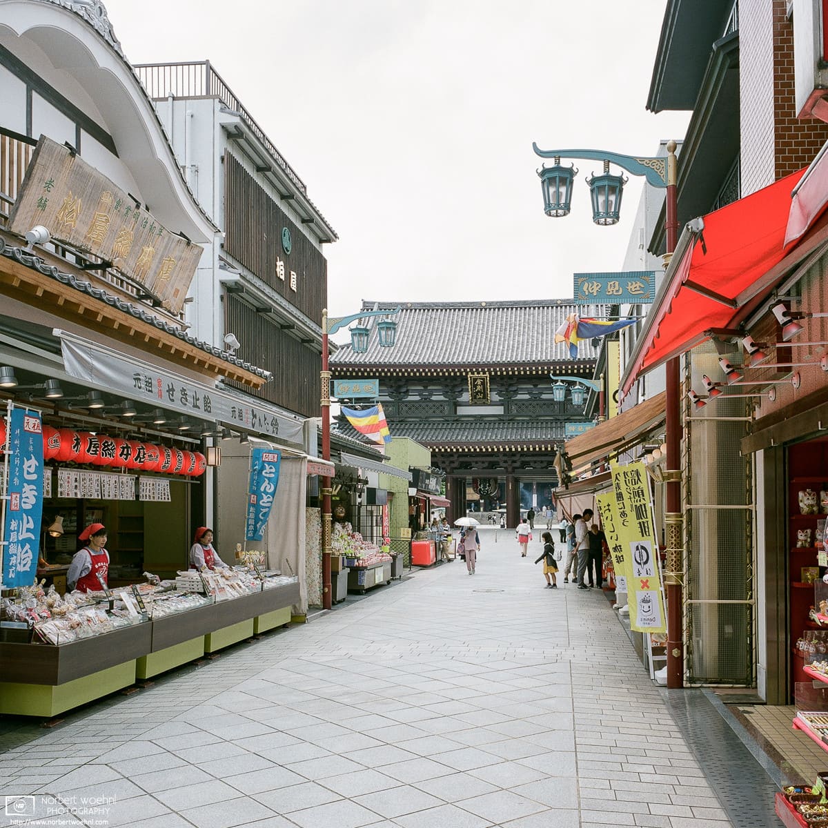 Approaching Kawasaki Daishi (Heiken-ji) Temple in Kawasaki, Japan, along a road lined with shops.