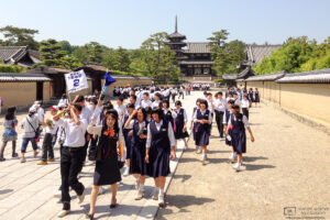 Students are taking a guided tour outside Hōryūji Temple (法隆寺) in Nara, Japan.