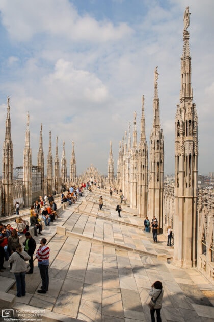 Tourists taking in the incredible views from the rooftop of Duomo di Milano, the cathedral church of Milan, Italy.
