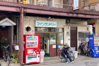 A man sitting on a chair is watching life outside a coin laundry at Kirigaoka in Kita-ku, Tokyo, Japan.