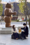 A young couple having a chat beside a bear statue outside the Marunouchi Oazo Building in Tokyo, Japan.